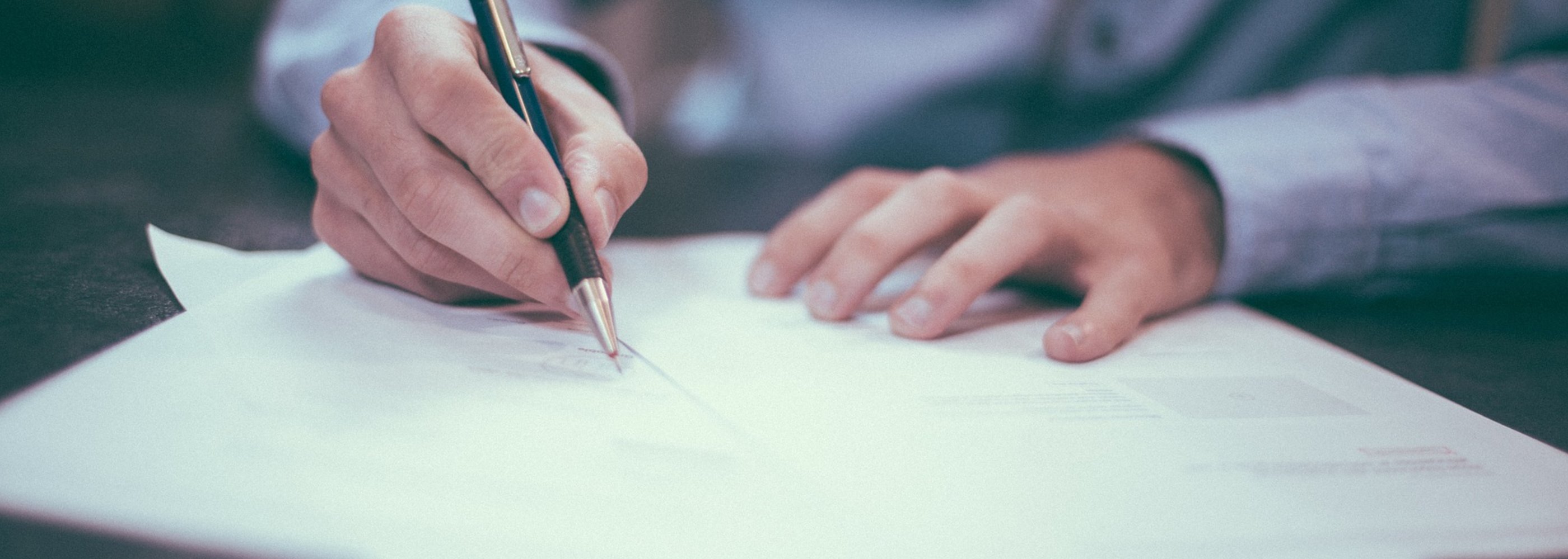 Hand with pen writing on paper